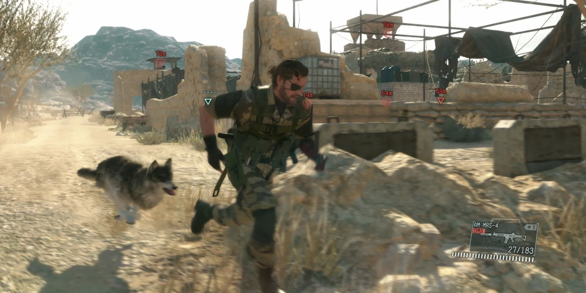 Big Boss (Snake) và chú chó D-Dog đang ẩn mình trong bụi rậm, quan sát môi trường xung quanh trong game Metal Gear Solid 5: The Phantom Pain.