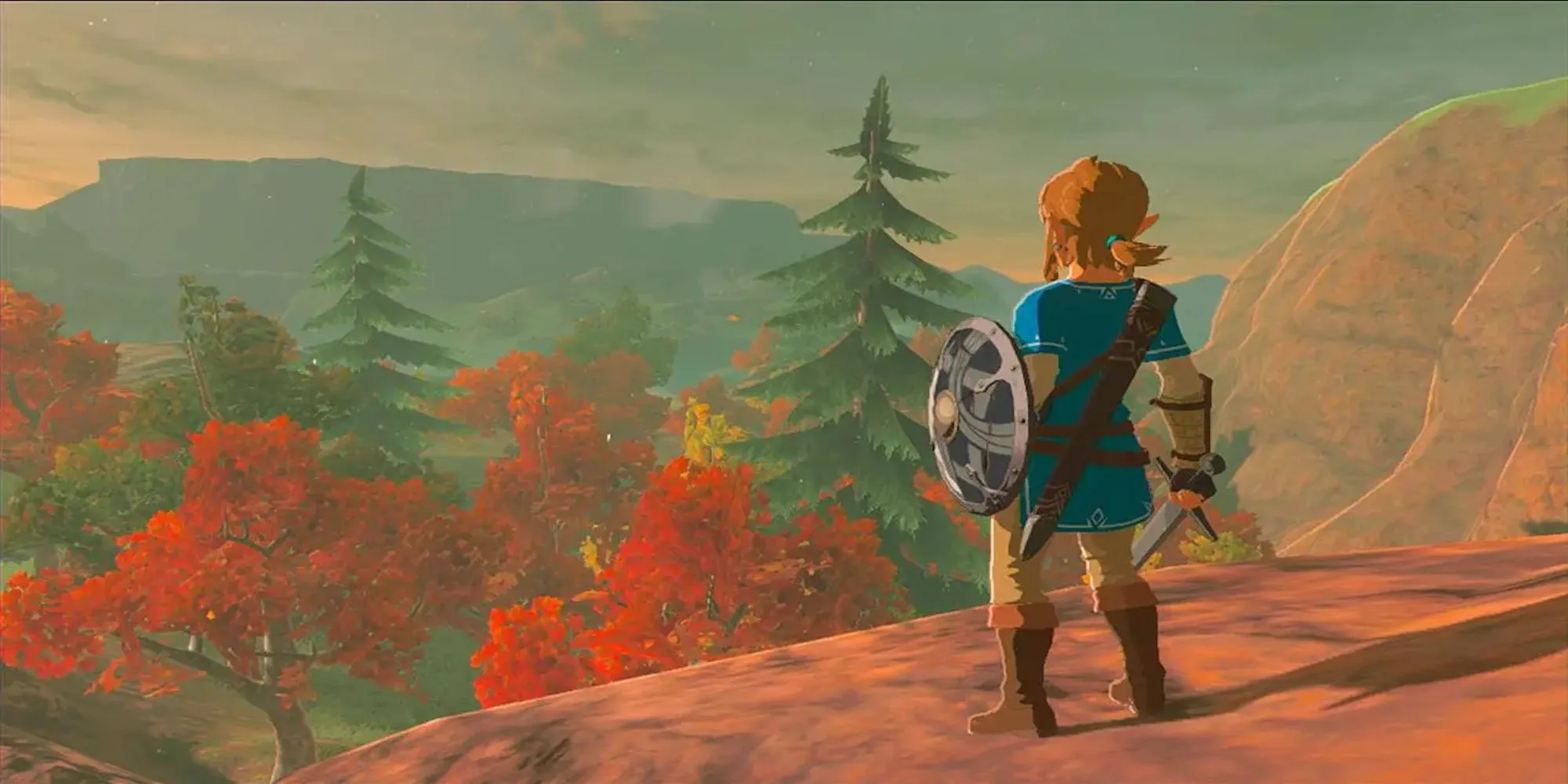 Link đứng trên đỉnh núi nhìn ra quang cảnh hùng vĩ của Hyrule trong The Legend of Zelda: Breath of the Wild, thể hiện thế giới mở rộng lớn.