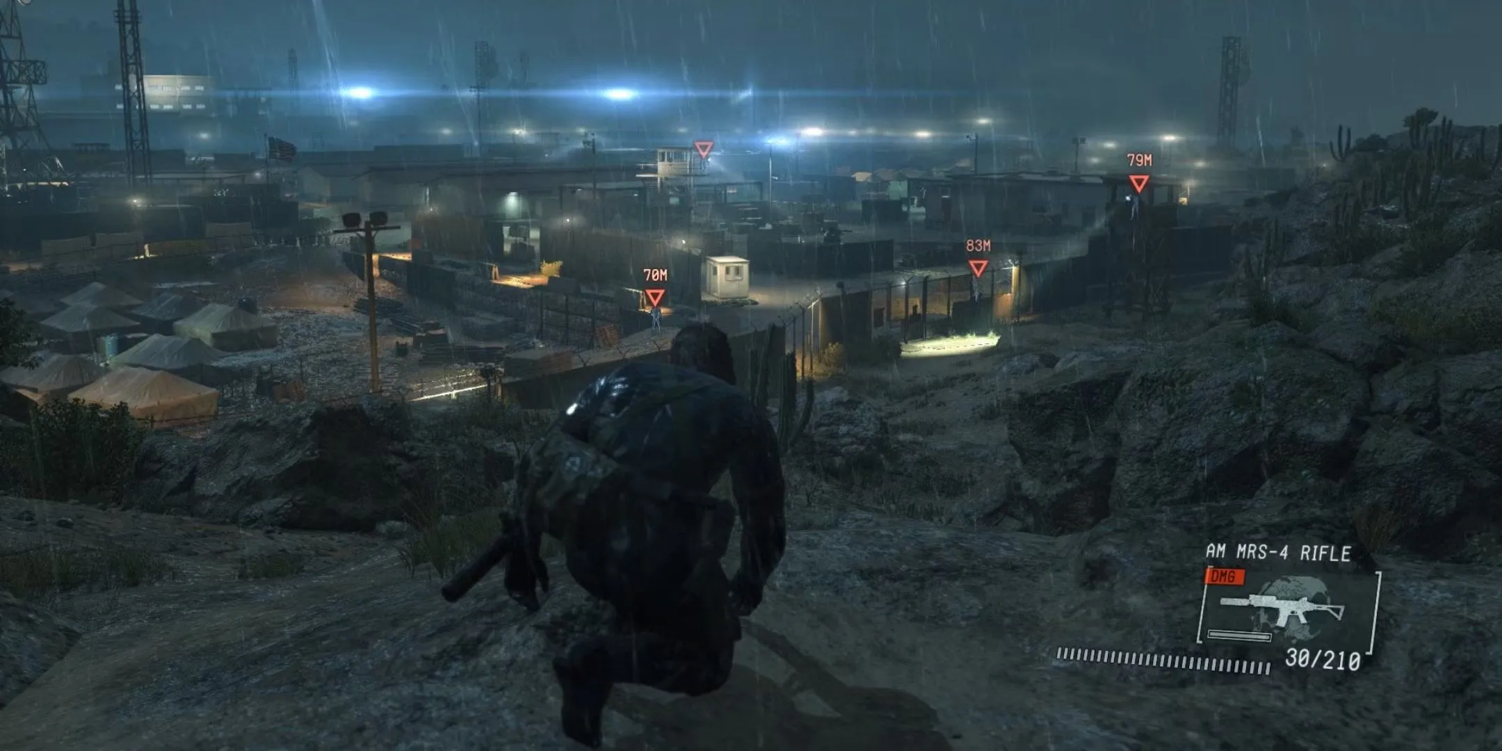 Snake quan sát một khu trại trong Metal Gear Solid 5 Ground Zeroes